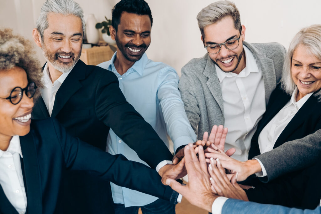 A group of cheerful best marketers join hands together in a show of unity.
